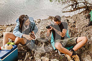 Couple in love camping forest hike. Food for hike and camping. Couple sit near bonfire eat and drink