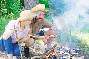 Couple in love camping forest roasting sausage at bonfire. Couple hungry tourists roasting sausages on sticks nature