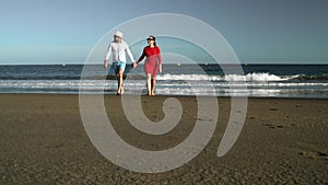 Couple in love carefree walking from the water on the beach. Picturesque ocean coast of Tenerife, Canarian Islands