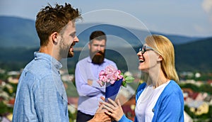 Couple in love dating while jealous husband fixedly watching on background. Couple romantic date lover present bouquet