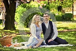 Couple in love enjoying picnic time and food outdoors. Beautiful people in love dating. Spring date. Couple relaxing at