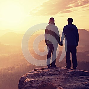 Couple in love enjoying tender moments during sunset . Young pair of hikers hand in hand on the peak of rock empires park