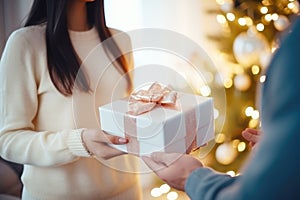 A couple in love exchanges gifts at home against the backdrop of a Christmas tree