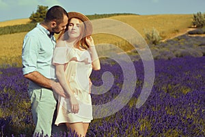 A couple in love in a field of lavender at sunset in good weather. Beautiful woman in a dress and straw panama with a man on the