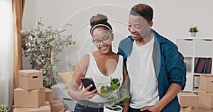 A couple in love are freshly moved into a new apartment the woman is standing in the middle of the living room holding a