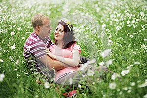 Couple in love guy and girl in a field of white daisies and green grass