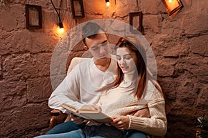 A couple in love, a guy and a girl reading a book. Christmas decorations in the photo studio Young teens