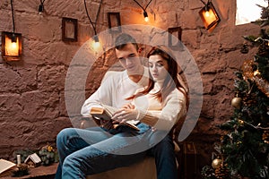 A couple in love, a guy and a girl reading a book. Christmas decorations in the photo studio Young teens