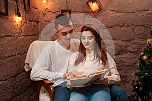 A couple in love, a guy and a girl reading a book. Christmas decorations in the photo studio Young teens