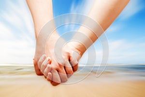 A couple in love hand in hand on the sunny beach