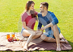 couple in love have fun in the park and drink smoothies and eating fruit at a picnic