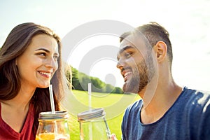 couple in love have fun in the park and drink smoothies and eating fruit at a picnic