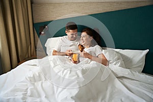 Couple in love is having breakfast in bed in hotel room