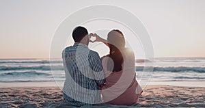 Couple, love and heart hands at beach for sunset, sky and care for romantic holiday, vacation or summer flare. Man