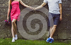 Couple in love is holding hands together in the old ancient town. Girl in pink dress and man in shorts are standing near the