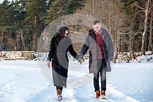 Couple in love holding hands and walking together in park in winter