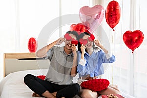 Couple in love holding red heart-shaped cards and smiling happy in Valentine's Day concept