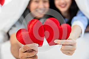 Couple in love holding red heart-shaped cards and smiling happy in Valentine\'s Day concept