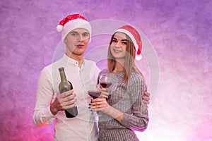 Couple in love holding wine bottle and glasses celebrating St. Valentine`s Day in studio