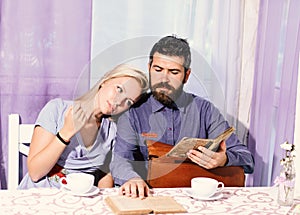 Couple in love holds cups of coffee at table. Woman and man with dreamy faces have an affair.