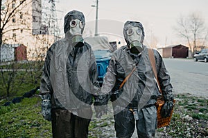 Couple in love holds hands in NBC protective suits and gas masks