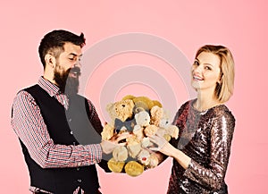 Couple in love holds heap of teddy bears on pink