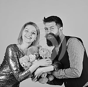 Couple in love holds heap of teddy bears on pink. Charity and love concept.