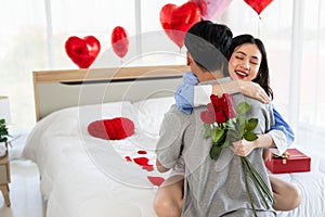 Couple in love hugging in the bedroom with rose and gift Valentine's Day concept