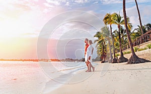 Couple in love hugging on sandy exotic beach while having evening walk by Trou-aux-Biches seashore on Mauritius island enjoying photo