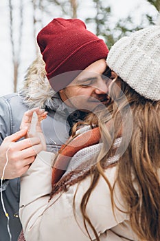 Couple in love hugs and kisses in a winter coniferous forest
