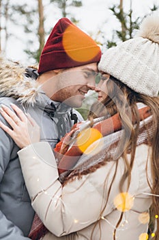 Couple in love hugs and kisses in a winter coniferous forest