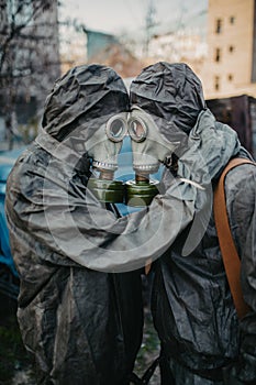 Couple in love hugs in NBC protective suits and gas masks