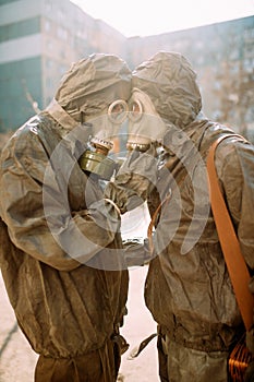 Couple in love hugs in NBC protective suits and gas masks