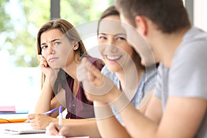 Couple in love and jealous classmate watching them photo