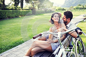 Couple in love joking together on a bench with bikes