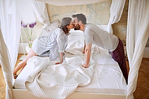 Couple in love kissing across canopy bed
