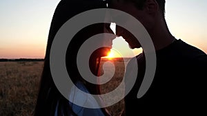 A couple in love kissing on the background of a summer sunset.
