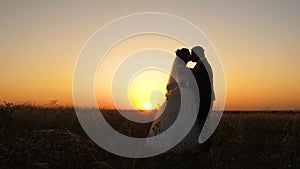 Couple in love is kissing. enamored newlyweds hug each other and stand in field against backdrop of a beautiful sunset