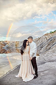 Couple in love kissing and hugging on the background of the rainbow and mountains. A man and a woman love each other. Fabulous