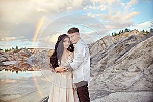 Couple in love kissing and hugging on the background of the rainbow and mountains. A man and a woman love each other. Fabulous
