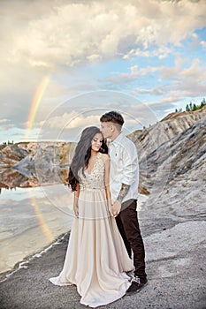 Couple in love kissing and hugging on the background of the rainbow and mountains. A man and a woman love each other. Fabulous