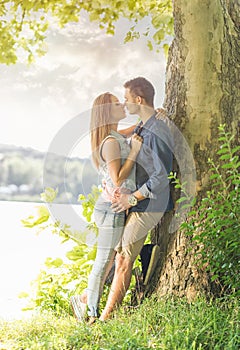 Couple in love on the lake, beneath the trees, kissing photo