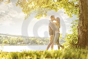 Couple in love on the lake, beneath the trees, kissing photo