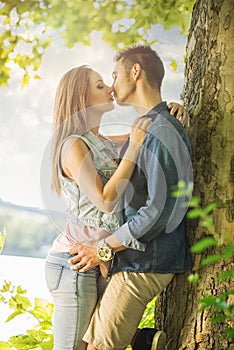 Couple in love on the lake, beneath the trees, kissing photo