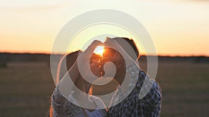 A couple in love makes a heart shape from their hands and kisses.