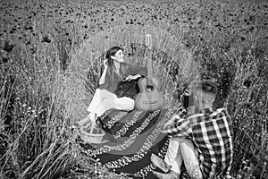 couple in love making photo on camera with acoustic guitar in summer poppy flower field, free time.