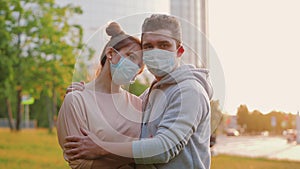 Couple in love in medical masks hug each other in city street during quarantine