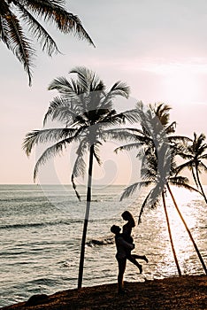 A couple in love meets a sunset on the sea among the palm trees. Man and woman at sunset. Honeymoon on the Islands. Honeymoon trip