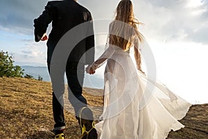 Couple in love in the mountains in wedding dresses at sunset