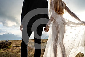 Couple in love in the mountains in wedding dresses at sunset